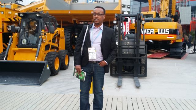 Mr. Kedir Ibrahim among construction machinery at an international trade fair